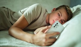 Adolescent mirant el mòbil al llit