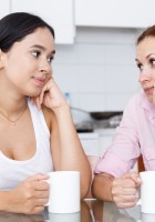 Madre e hija hablando con una taza en la mano.